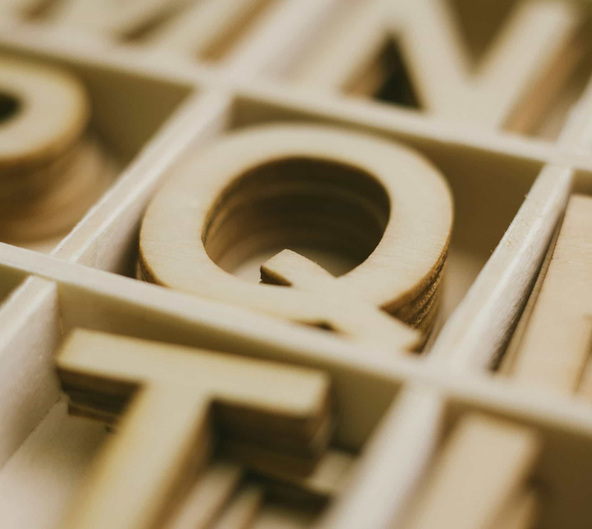 A letter Q made from wood as part of a puzzle with letters